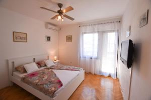 Schlafzimmer mit einem Bett, einem Deckenventilator und einem TV in der Unterkunft Room Vesna in Primošten