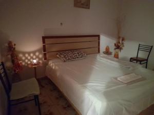 a bedroom with a large white bed and a chair at Cortina House Berat in Kuçovë