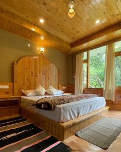 a bedroom with a large bed with a wooden ceiling at The Village View Homestay in Jibhi