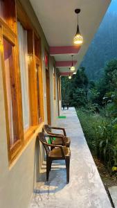 a row of chairs sitting on the porch of a house at The Village View Homestay in Jibhi