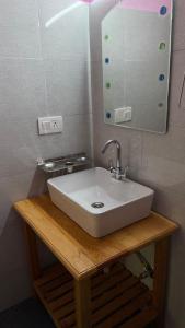 a bathroom with a white sink and a mirror at The Village View Homestay in Jibhi
