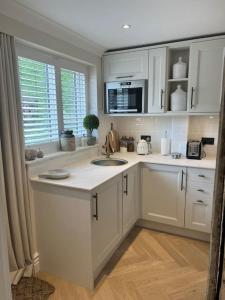 a kitchen with white cabinets and two sinks in it at Boutique style self contained annexe with garden in Mursley