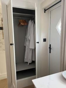 um armário branco com roupas brancas em Boutique style self contained annexe with garden em Mursley