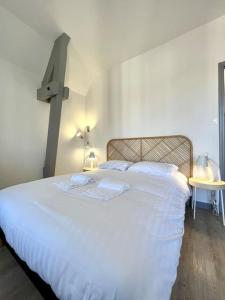 um quarto com uma cama branca e uma cruz na parede em Le Dolce 65m2 Centre de Dijon 4 personnes em Dijon