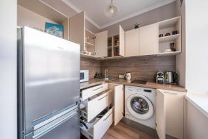 a kitchen with a refrigerator and a washer and dryer at Charming Latvian classic style apartment in Rīga