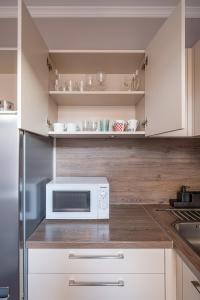 a kitchen with white cabinets and a microwave at Charming Latvian classic style apartment in Rīga