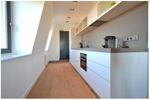 uma cozinha com armários brancos e piso em madeira em Residence Ruimzicht - Baddomburg em Domburg