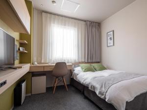 a bedroom with a bed and a desk with a television at Fujieda Park Inn Hotel in Fujieda