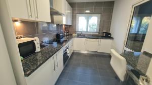 a kitchen with white cabinets and black counter tops at 240 Front line beach La Cala in La Cala de Mijas