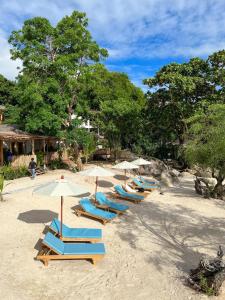 a row of lounge chairs and umbrellas on a beach at Siam Cookies Cottage in Haad Pleayleam