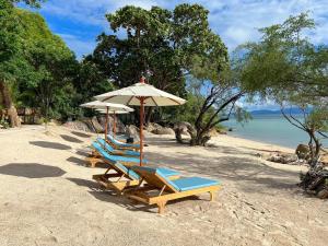 Haad Pleayleam的住宿－Siam Cookies Cottage，海滩上的2把躺椅和1把遮阳伞