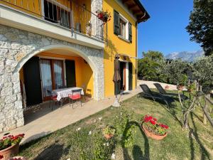 ein gelbes Haus mit einem Tisch und Stühlen auf einer Terrasse in der Unterkunft Villa dei Roveri in Tignale