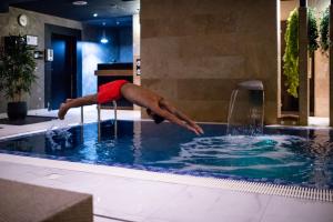 a man jumping into a pool in a swimming pool at Amsterdam Hotel in Belgrade
