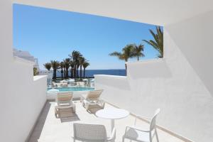 a balcony with chairs and a table and a pool at Iberostar Selection Lanzarote Park in Playa Blanca