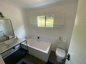 a bathroom with a tub and a sink and a toilet at Caversham Woods in Lidgetton