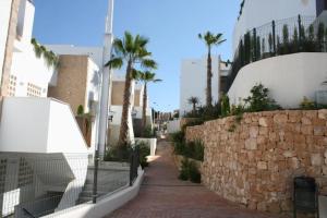 a street with palm trees and a stone wall at Nova Beach Super cool seaview apartment in Santa Pola