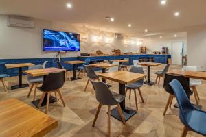 a restaurant with tables and chairs and a tv on the wall at Hôtel Le Cyrano Bergerac in Bergerac