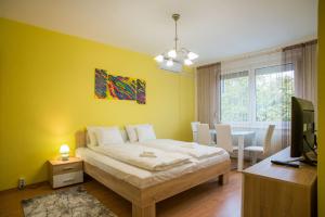 a bedroom with a bed and a table and a television at Otthon-Laksz apartman in Nyíregyháza