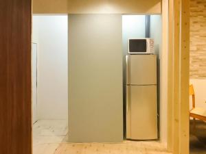 einen Kühlschrank mit einer Mikrowelle darüber in der Unterkunft Relak Guest House 登別 Station in Noboribetsu