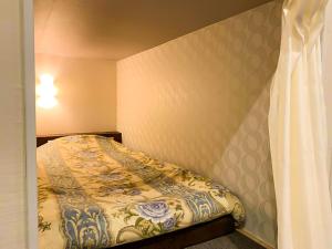 een kleine slaapkamer met een bed in de hoek bij Relak Guest House 登別 Station in Noboribetsu