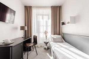 a bedroom with a bed and a desk and a window at Hotel Pivoňka in Slavonice