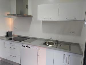 una cocina blanca con fregadero y armarios blancos en Excelente piso con aparcamiento privado, en Palos de la Frontera