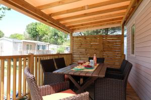 a patio with a table and chairs on a deck at Happy Camp mobile homes in Camping Village La Masseria in Gallipoli