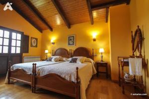 a bedroom with a large bed with yellow walls at Casa Rural La Cuesta in Villarmil