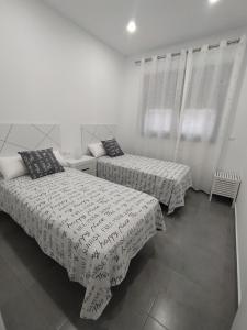 two beds in a room with white walls and windows at Excelente piso con aparcamiento privado in Palos de la Frontera