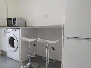 cocina con lavadora y 2 taburetes en Excelente piso con aparcamiento privado en Palos de la Frontera