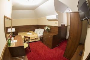 Habitación pequeña con cama y escritorio. en Hotel Poniatowski, en Radom