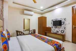 una camera con letto, TV e sedia di FabHotel Frolic a Haridwār