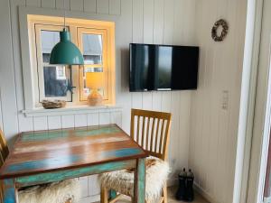 a dining room with a wooden table and a flat screen tv at Harbour Living in Hvide Sande