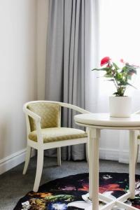 a chair and a table and a vase with a flower at Hotel type living, spacious, central, secure,wifi! in Cape Town