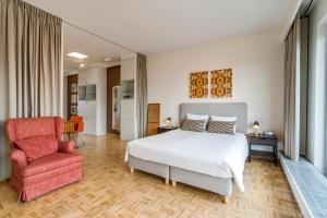 1 dormitorio con 1 cama blanca y 1 silla roja en Fuths Loft Penthouse 85 en Amberes