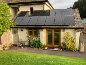 una casa con paneles solares en el techo en Orchard House Garden Studio - Relax Refresh Return, en Wiveliscombe