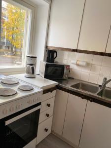 a kitchen with a stove and a sink and a microwave at Citimotel in Lappeenranta