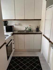 a small kitchen with white cabinets and a sink at Citimotel in Lappeenranta