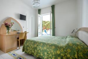 Schlafzimmer mit einem Bett, einem Schreibtisch und einem Fenster in der Unterkunft Hotel Il Pino in Praiano