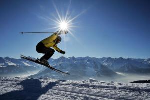 um homem a voar pelo ar enquanto monta esquis em Ferienwohnung Prokosch em Kirchdorf in Tirol
