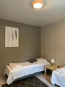 a bedroom with two beds and a lamp and a table at Citimotel in Lappeenranta