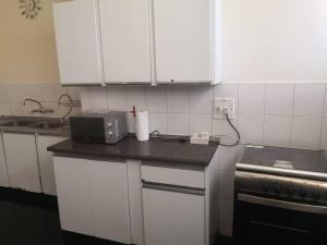 a kitchen with white cabinets and a microwave on a counter at Spacious Executive Holiday Apartment In Bulawayo in Bulawayo