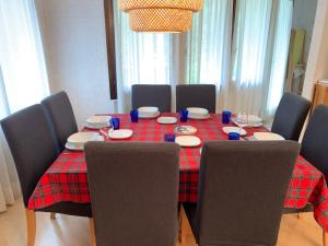 une table à manger avec des chaises et un tissu de table rouge dans l'établissement SPINALE casa in centro, arrivi con gli sci! SANIFICAZIONE A VAPORE, à Madonna di Campiglio