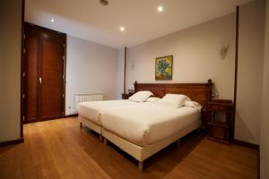 a bedroom with a large white bed and wooden floors at Hotel Villalegre in Avilés