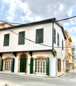 a white building with green doors on a street at The Old Town Heritage House Platform 357 in Nicosia