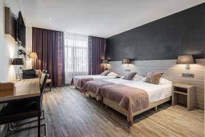 a hotel room with two beds and a desk at Hotel Milano in Rotterdam