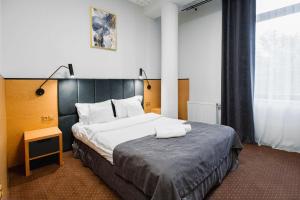 a hotel room with a large bed with two towels on it at Hotel Poniatowski in Radom