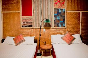 a room with two beds and a lamp and a table at Pao's Leisure Homestay in Ha Giang