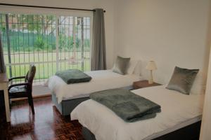two beds in a room with a window and a chair at Moonflower Cottages in Johannesburg +61 photos