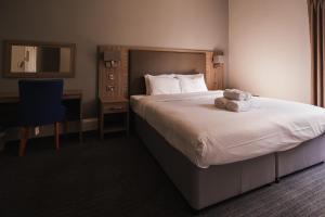 a hotel room with a bed with a towel on it at St Andrews Town Hotel in Droitwich